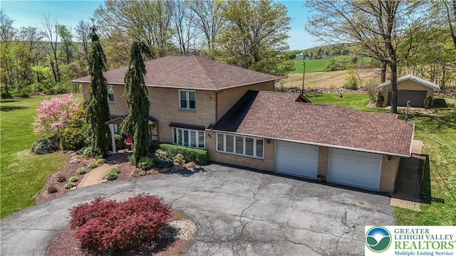 traditional-style house with asphalt driveway, a front yard, a garage, and roof with shingles