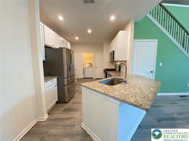 306 Redclover Ln, Upper Macungie Twp, PA 18104 - kitchen featuring washer and dryer, white cabinets, dark wood-type flooring, stainless steel appliances, and a sink
