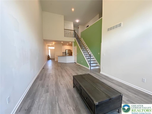 306 Redclover Ln, Upper Macungie Twp, PA 18104 - unfurnished living room with a towering ceiling, wood finished floors, stairs, and baseboards
