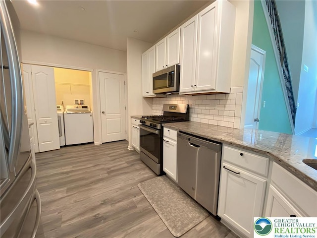 306 Redclover Ln, Upper Macungie Twp, PA 18104 - kitchen featuring stainless steel appliances, washer and clothes dryer, white cabinetry, tasteful backsplash, and light wood finished floors