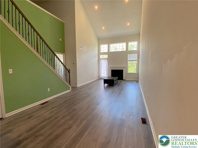 306 Redclover Ln, Upper Macungie Twp, PA 18104 - unfurnished living room featuring a fireplace, wood finished floors, a high ceiling, baseboards, and stairway