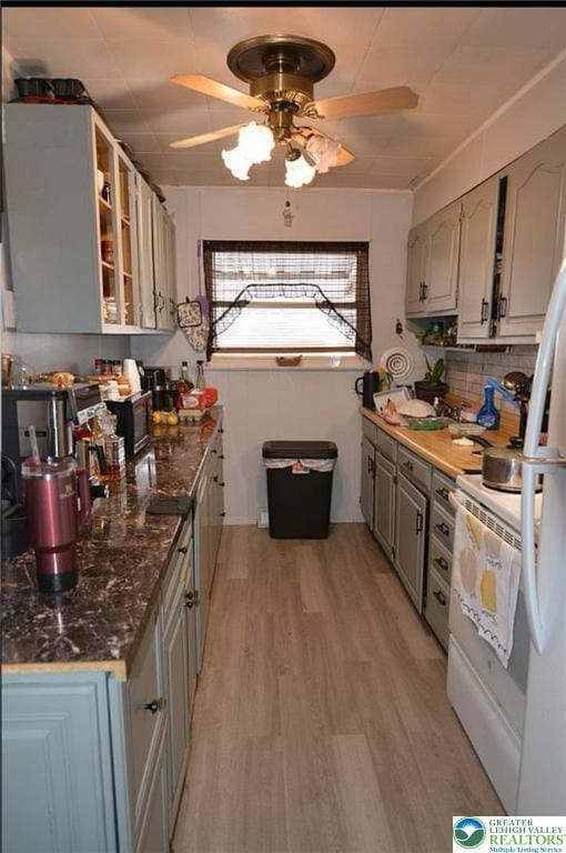 kitchen featuring range, light wood-style flooring, ceiling fan, gray cabinets, and glass insert cabinets