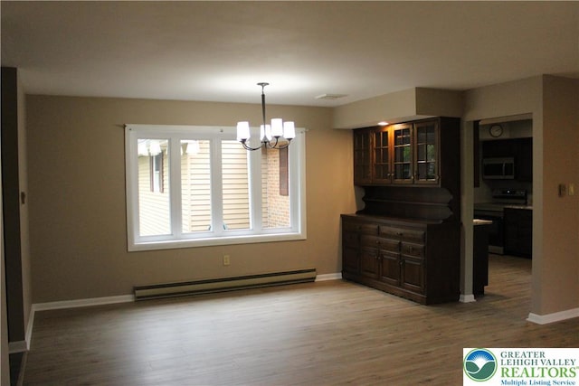 unfurnished dining area with baseboard heating, a chandelier, baseboards, and wood finished floors
