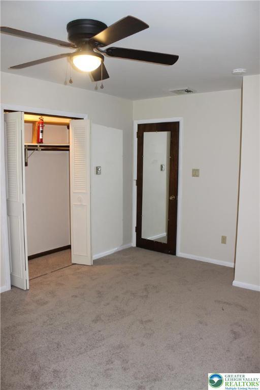 unfurnished bedroom with carpet floors, a closet, baseboards, and ceiling fan