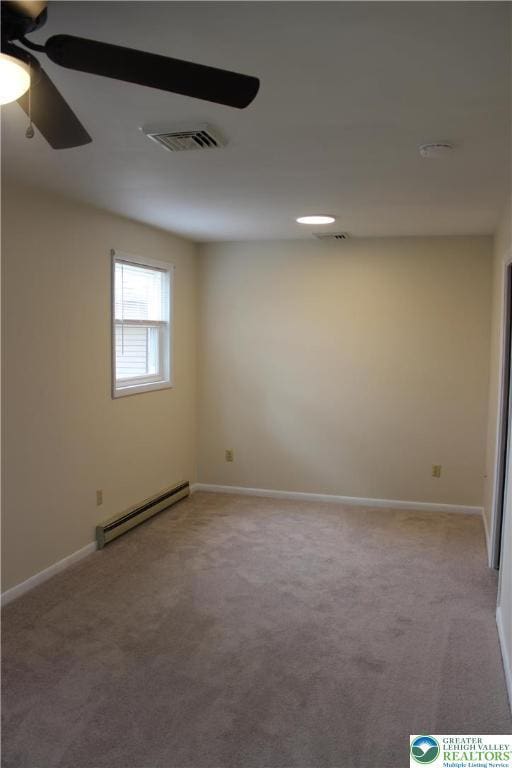spare room featuring a baseboard heating unit, carpet floors, and baseboards