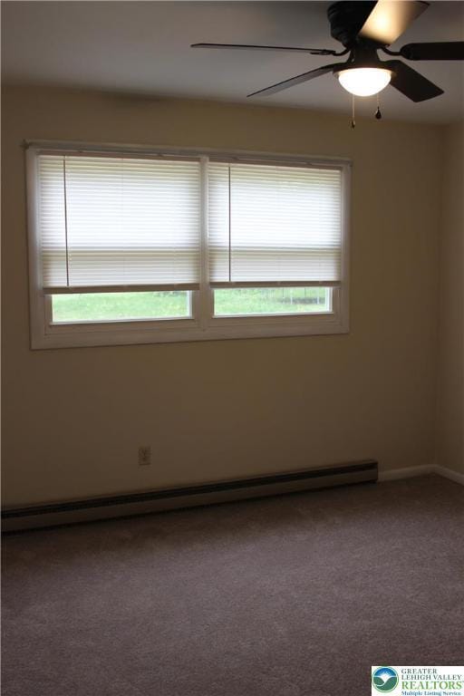 carpeted spare room featuring a baseboard heating unit and baseboards