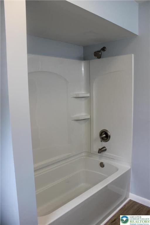 bathroom with wood finished floors, tub / shower combination, and baseboards