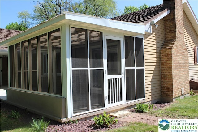 view of side of property with a sunroom and a chimney