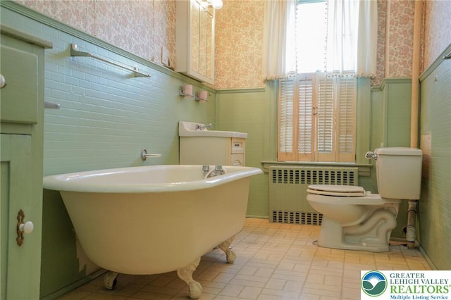 415 Hazle St, Tamaqua Borough, PA 18252 - bathroom featuring wallpapered walls, radiator heating unit, wainscoting, a freestanding tub, and toilet