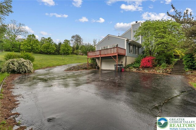 view of side of home featuring asphalt driveway, stairs, a chimney, a yard, and a garage