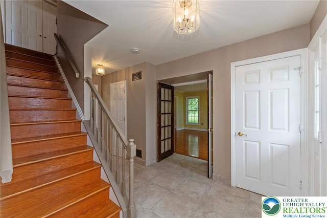staircase featuring tile patterned floors, baseboards, and a chandelier