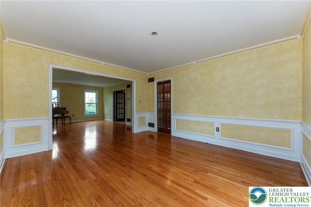 spare room featuring ornamental molding, wood finished floors, and wainscoting