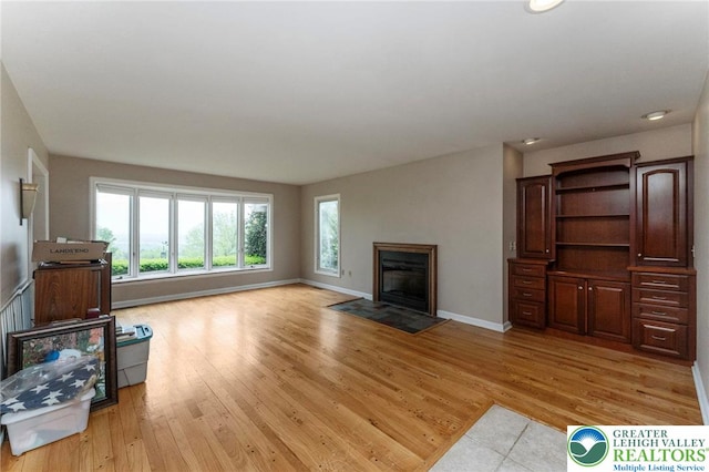 unfurnished living room with a fireplace, baseboards, light wood-style flooring, and recessed lighting