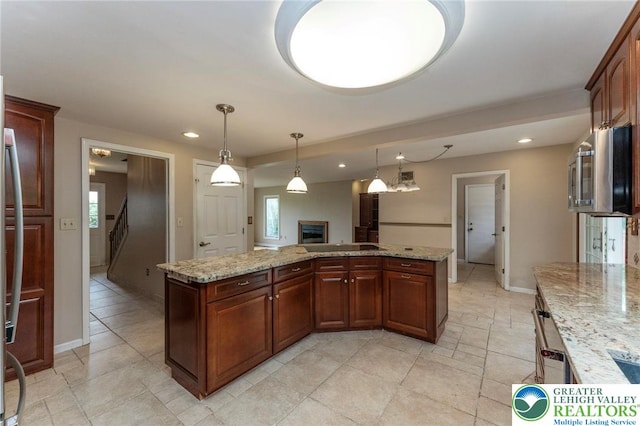 kitchen with a fireplace, recessed lighting, hanging light fixtures, baseboards, and a kitchen island