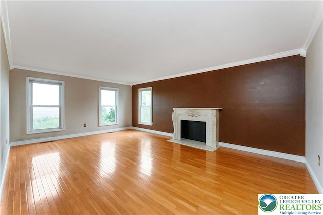unfurnished living room with ornamental molding, light wood-style flooring, baseboards, and a premium fireplace