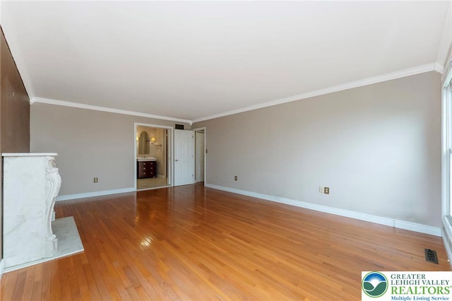 unfurnished living room featuring baseboards, light wood finished floors, and ornamental molding