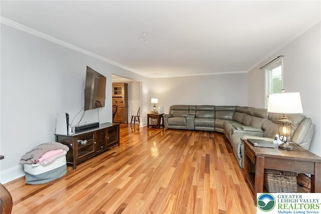 living room featuring light wood-style floors, ornamental molding, and baseboards