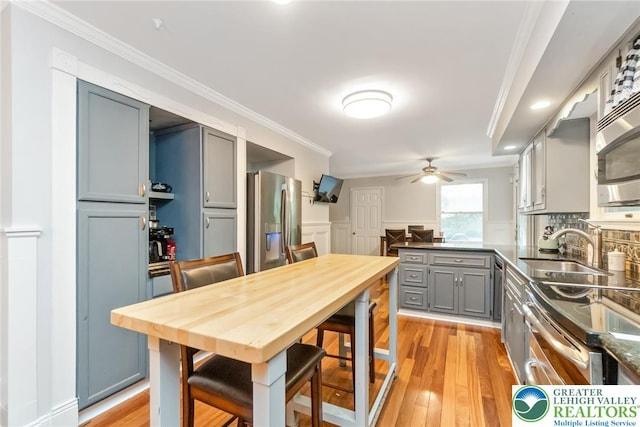kitchen with appliances with stainless steel finishes, gray cabinets, ceiling fan, a sink, and dark countertops
