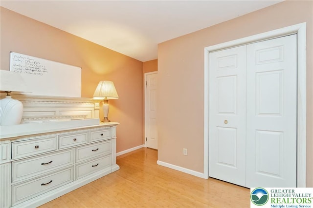 bedroom with light wood-style floors, baseboards, and a closet