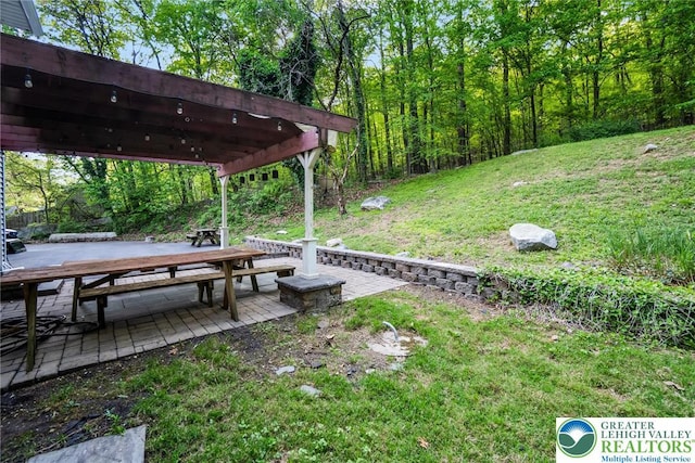 view of green lawn with a pergola and a patio