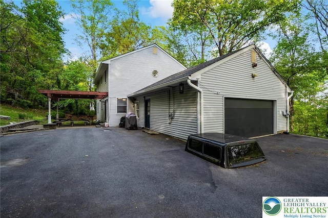 view of side of home with asphalt driveway and a garage