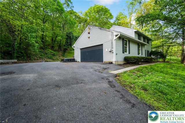 view of home's exterior featuring an attached garage and asphalt driveway