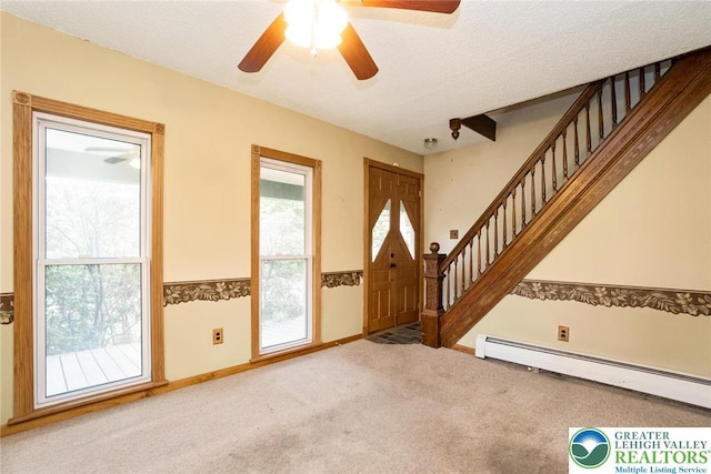entrance foyer with stairway, baseboard heating, carpet, and ceiling fan
