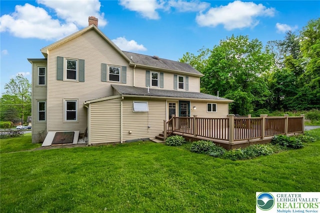 back of property featuring a deck, a chimney, and a yard