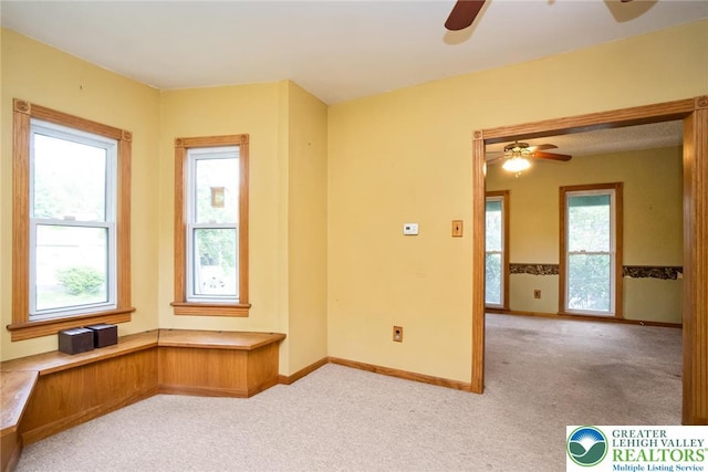 empty room featuring a ceiling fan, light carpet, and baseboards