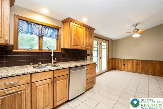 kitchen featuring dishwasher, a sink, lofted ceiling, wainscoting, and ceiling fan