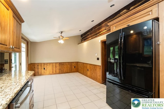 kitchen with black refrigerator with ice dispenser, a wainscoted wall, wooden walls, dishwasher, and ceiling fan