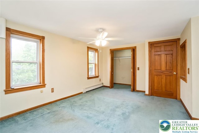 unfurnished bedroom featuring a baseboard heating unit, carpet floors, baseboards, and a closet