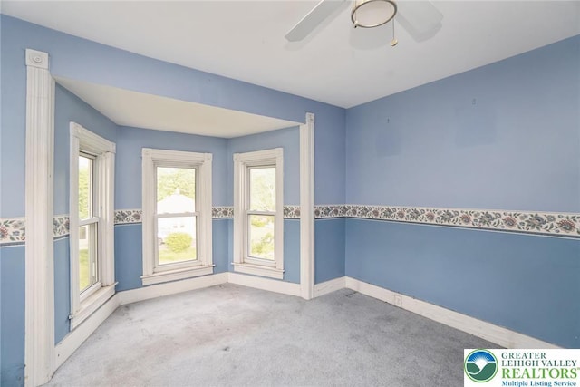 carpeted spare room featuring baseboards and ceiling fan