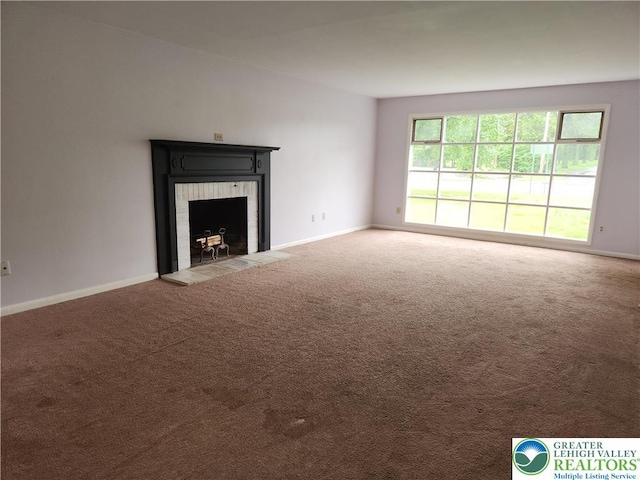 unfurnished living room with carpet, a fireplace with flush hearth, and baseboards