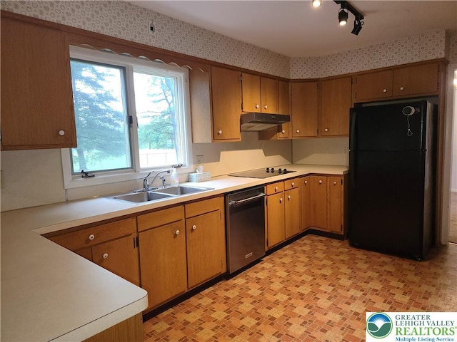 kitchen featuring black appliances, a sink, light countertops, under cabinet range hood, and wallpapered walls