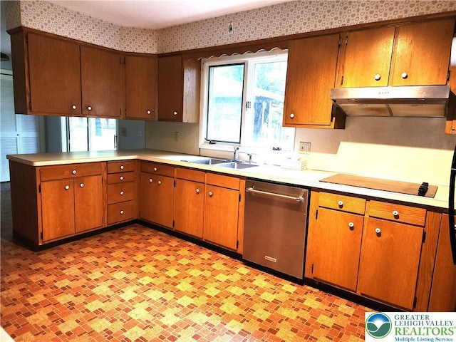 kitchen featuring dishwasher, a sink, under cabinet range hood, light countertops, and wallpapered walls