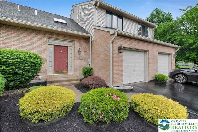 view of front of property with brick siding, entry steps, driveway, a garage, and a shingled roof