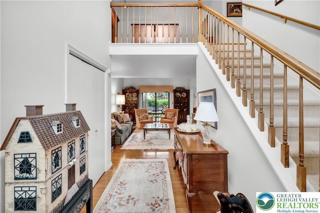 foyer with a high ceiling, wood finished floors, and stairs