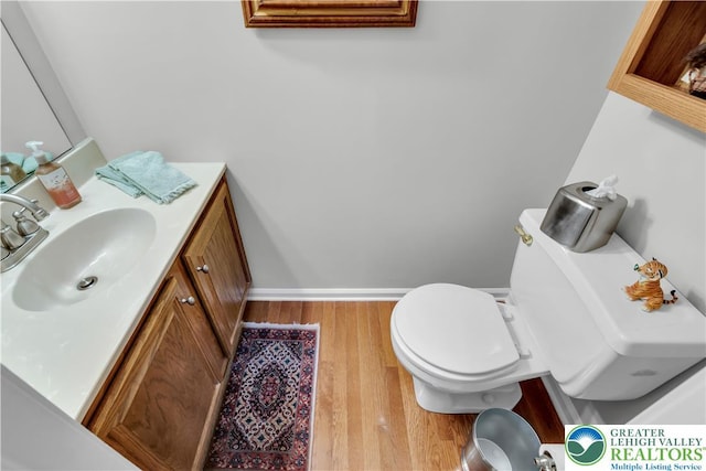 bathroom with wood finished floors, vanity, toilet, and baseboards