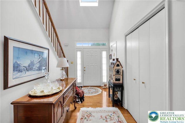 foyer entrance featuring high vaulted ceiling and light wood finished floors