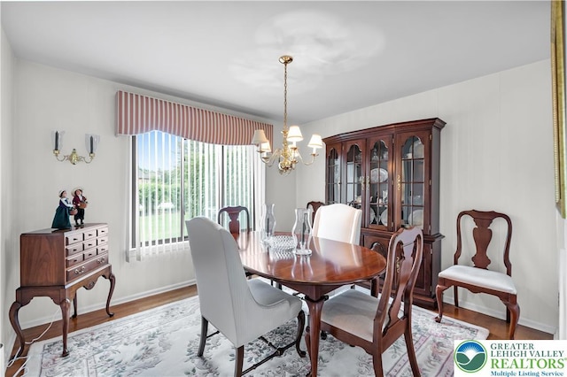 dining space with a chandelier, wood finished floors, and baseboards