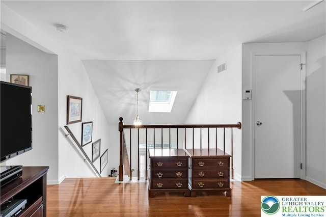 hall with an upstairs landing, a skylight, and wood finished floors