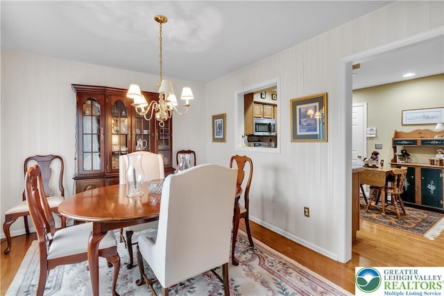 dining room featuring a chandelier, wood finished floors, and baseboards