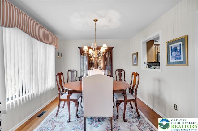 dining area featuring wood finished floors, baseboards, and a chandelier