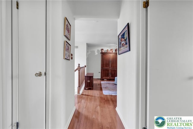 corridor with light wood-type flooring and baseboards