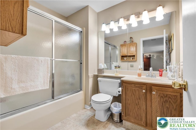 bathroom with tile patterned floors, shower / bath combination with glass door, vanity, and toilet