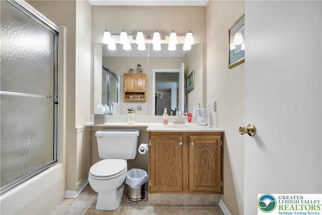bathroom with tile patterned floors, toilet, vanity, baseboards, and shower / bath combination with glass door