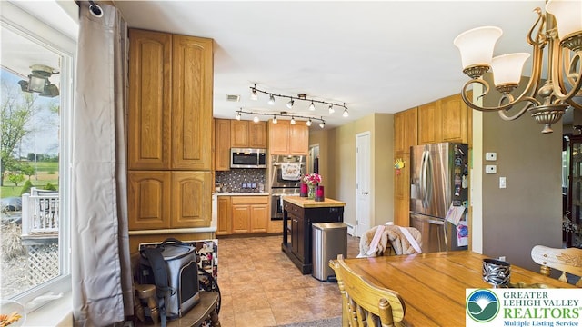 4168 Orefield Rd, South Whitehall Twp, PA 18104 - kitchen with appliances with stainless steel finishes, a chandelier, decorative backsplash, a center island, and brown cabinets