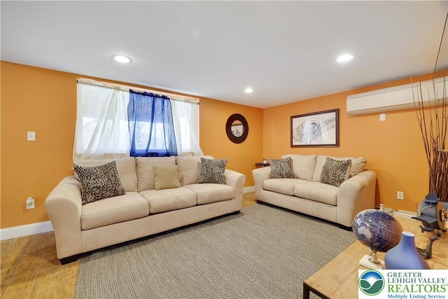 living room featuring an AC wall unit, baseboards, recessed lighting, and wood finished floors