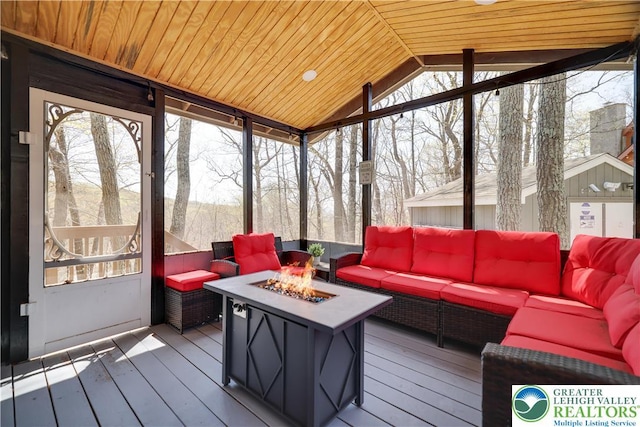 sunroom / solarium with an outdoor living space with a fire pit, lofted ceiling, and plenty of natural light